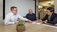 Three members of the Business and Analytics team meet in a conference room.